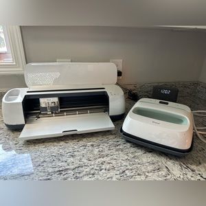 Rose gold cricut maker, turquoise heat press, and supplies.